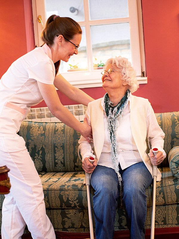 Caretaker helping elderly woman up