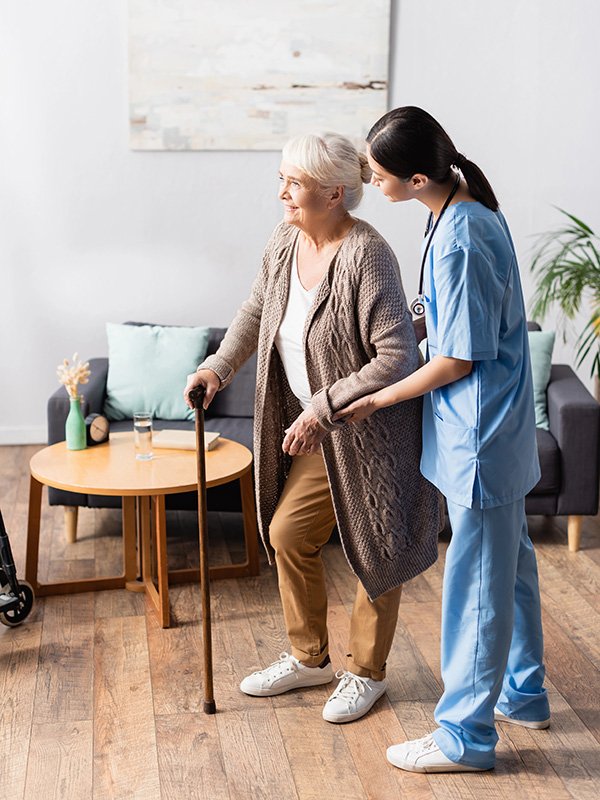 Cargiver helping elderly woman walk