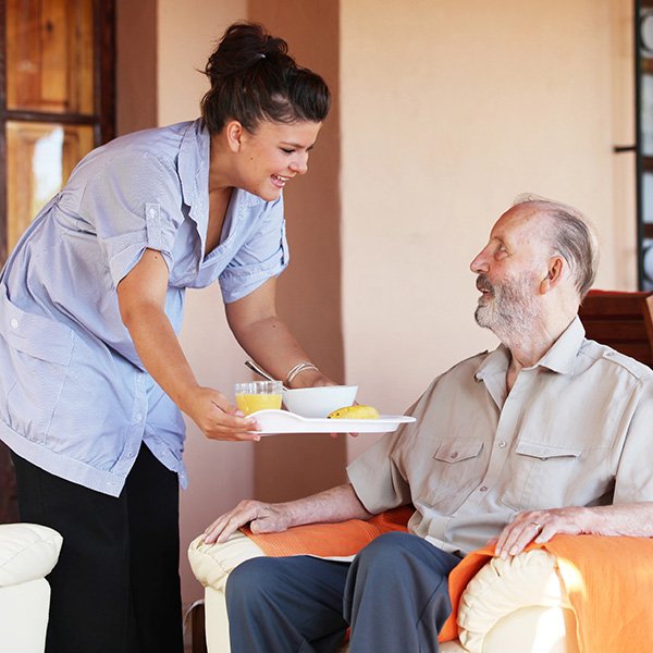 Caregiver giving food to elderly man